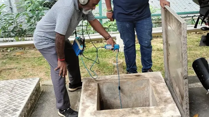 DJR technician lowering an inspection probe into an open drain chamber